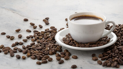 Cup of Coffee on a Saucer with Spilled Coffee Beans on a Marble Counter