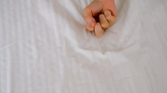 Woman holding man's hand lying in bed making love, hands close-up. Sex, intimate life, pleasure and love concept. Two lovers having a sex holding hands, sensual gesture.