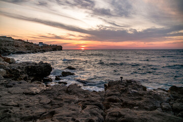 Sunset Sea Coastline Greece - A scenic view of a sunset over the sea with rocky coastline in Greece.