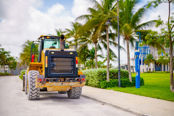 Wheel loader by a park with palms
