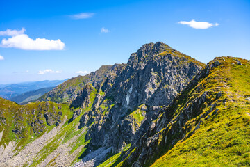 The breathtaking landscape of Dumbier Mountain reveals majestic rock formations under a clear blue sky. Hikers can enjoy stunning views of the Low Tatras at this popular outdoor destination.