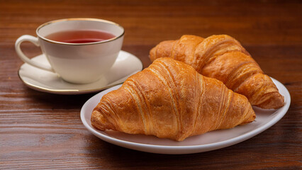 Plate of Croissants with a Cup of Tea on a Saucer on a Wooden Table