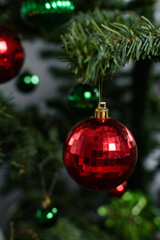 red Christmas decorations on a christmas tree, sparkly red christmas tree baubles on artificial tree, closeup view of red christmas tree ornaments