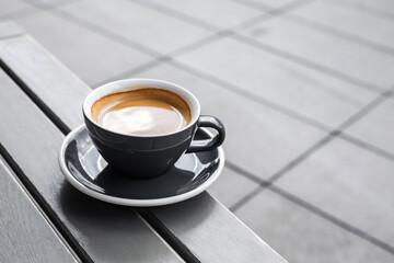 A cup of black coffee on the table of a city cafe or bakery terrace