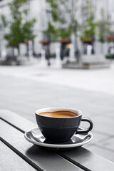 A cup of black coffee on the table of a city cafe or bakery terrace