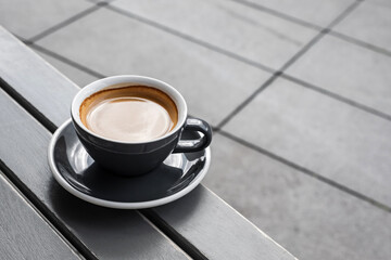 A cup of black coffee on the table of a city cafe or bakery terrace