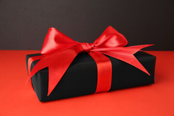 Gift box with red bow on color background