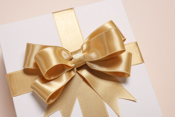 Gift box with bow on beige background, closeup