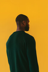 A man in a green sweater stands with his back to the camera.