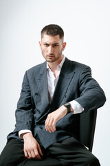 Portrait of handsome man, fashion model. Sits on chair.
