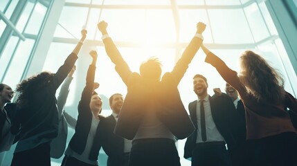 Ecstatic business team celebrating their success with raised arms in front of an illuminated window.