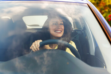 Smiling woman driving vehicle on road on bright sunny day, lady enjoying her new automobile, view...