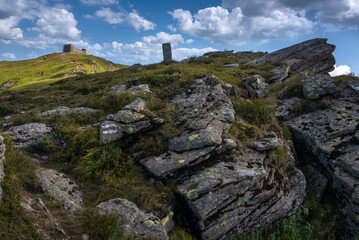 Fototapeta premium landscape of mountains through stones, border post, silhouettes of mountains and the old observatory on Mount Pip Ivan in the distance. Chornohirsky ridge, Carpathians, Ukraine