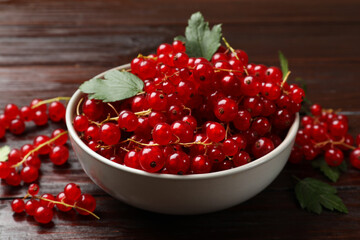 Fresh red currants in bowl on wooden table, closeup
