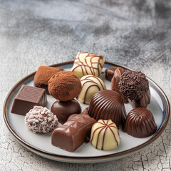 An assortment of white and dark brown chocolates decorated with almonds and arranged in a World Chocolate Day layer with a gray background