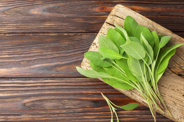 Green sage leaves on wooden table, top view. Space for text