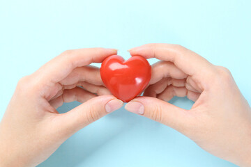 Obraz premium Woman with red heart on light blue background, closeup