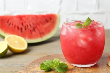 Tasty watermelon drink in glass, mint and fresh fruits on wooden table, closeup