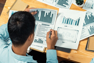 Fototapeta premium Top view diverse group of business analyst team analyzing financial data report paper on meeting table. Chart and graph dashboard by business intelligence analysis. Meticulous