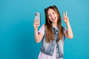 Photo portrait of charming little girl selfie photo v-sign wear trendy jeans outfit isolated on blue color background