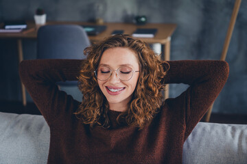 Photo of cheerful lovely cute woman wear trendy clothes hold arms behind head enjoy rest indoors...