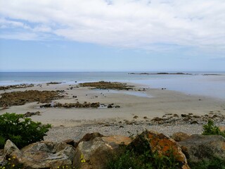 Bord de mer avec marée basse, ciel bleu et nuage, récifs rocheux dans le Finistère en France