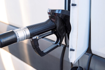 Closeup of a fuel nozzle in the car tank. Process of refilling a white transporter bus at a gas...