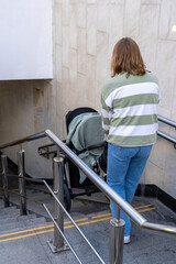 A person carefully guides a stroller down a set of stairs in a contemporary urban environment