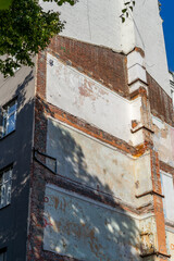 An old building displays its weathered walls with peeling paint, revealing layers of history under a bright blue sky