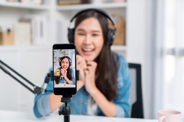 Obraz premium Selective focus phone in host channel of young beautiful Asian in creative broadcaster talking online explaining to promote marketing or consultant in daily life with listener at studio. Stratagem.
