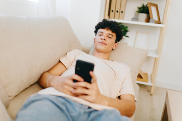 Young man relaxing on a sofa using smartphone in a cozy living room, enjoying leisure time and modern lifestyle Soft tones create a calm atmosphere for relaxation