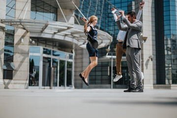Business professionals jumping and celebrating success outside a modern office building, exuding joy and motivation. Capturing teamwork and achievement in a corporate environment.