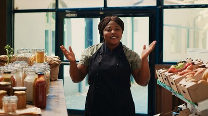 Local retailer promoting her eco friendly small business online, recording video while she presents variety of homemade sauces and additives free bulk products in jars. Proud farmer. Tripod shot.