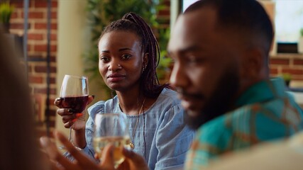 African american woman at apartment party watching man share interesting story, having crush on him. Guest at home gathering in love with charming BIPOC host captivating friends with tale