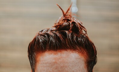 close-up of dyed red female hair in a bun on a brown background