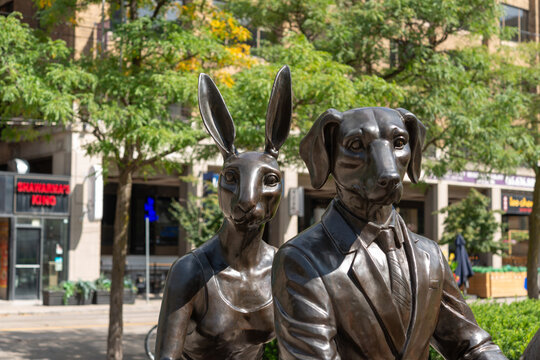 frontal view of "Rabbitwoman" and "Dogman" by Gillie and Marc's public sculpture, "He Was on a Ride to a Safer Place with Rabbitwoman and Dogman" on view at David Pecaut Square in Toronto, Canada