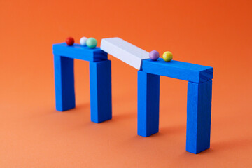 Group of separate spheres in interrupted step of bridge made of wooden figures