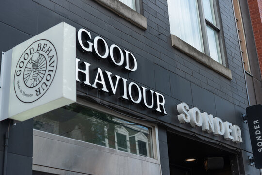 exterior signage at Good Behaviour, a sandwich shop, located at 335 Queen Street West in Toronto, Canada (next door is Sonder The Beverley, a hotel)