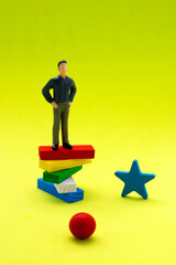 Executive on pedestal made of wooden figures of different colors observing the whole panorama from above