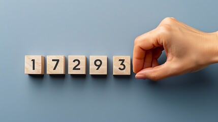 Hand Arranging Numbered Wooden Blocks on a Gray Surface