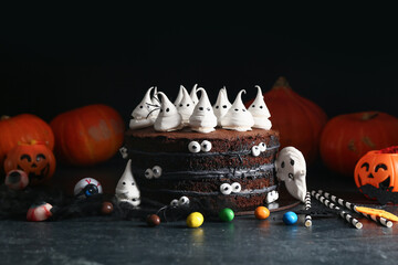 Tasty Halloween cake with ghosts, eyes, spiders and candies on black background