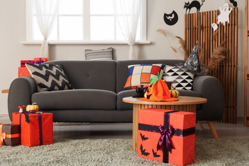 Interior of festive living room with grey sofa, Halloween decorations and gift boxes