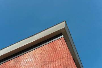 skyward glance at the corner of a brick building and metal trim edge on a blue sky