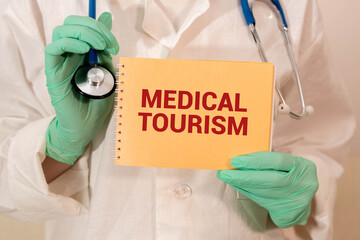 Doctor holding a pen and card with text medical tourism, medical concept.