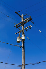 Wooden Telephone Pole With High Voltage Sign On Blue Sky