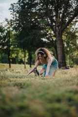 A lovely girl performs warm-up exercises in a sunlit park setting, enjoying music with headphones...