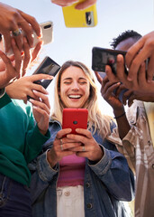 Low angle view of a group of young teenagers friends using cell phones and walking in the city....