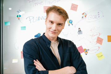 Portrait of happy professional young caucasian businessman crossing arm while looking at camera with confident at creative business meeting with colorful sticky notes and mind map. Immaculate.