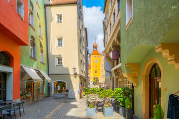A narrow alley with shops and sidewalk cafes with the Brückturm clock tower and gate in the...