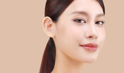 Fototapeta premium Close up face of beautiful young Asian woman with K beauty style makeup and perfect skin on isolated beige brown background. Facial and skin care concept for commercial advertising.